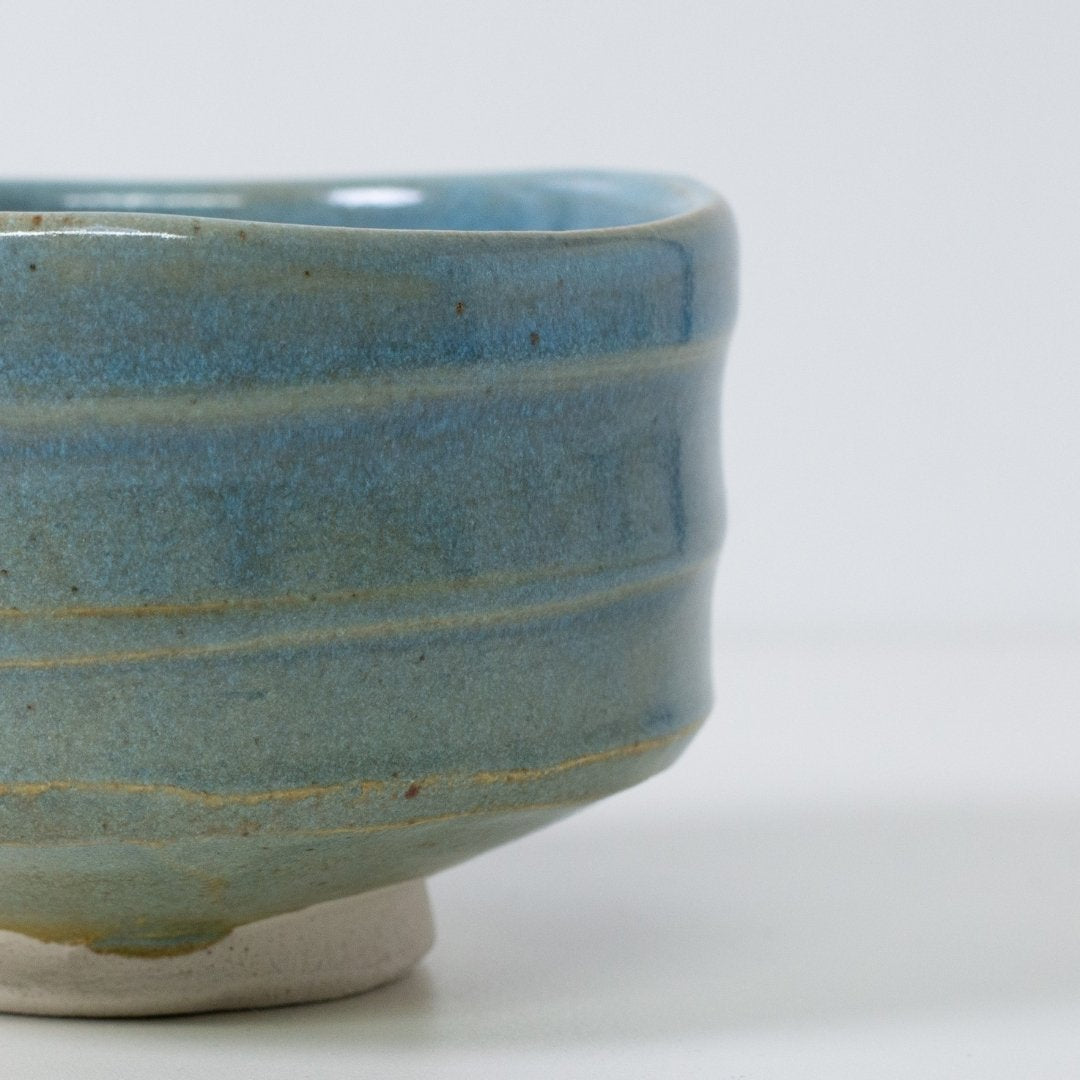 Close-up detail of "Summer Sky" matcha chawan bowl showing the translucent blue glaze revealing warm earthen brown clay ridges.