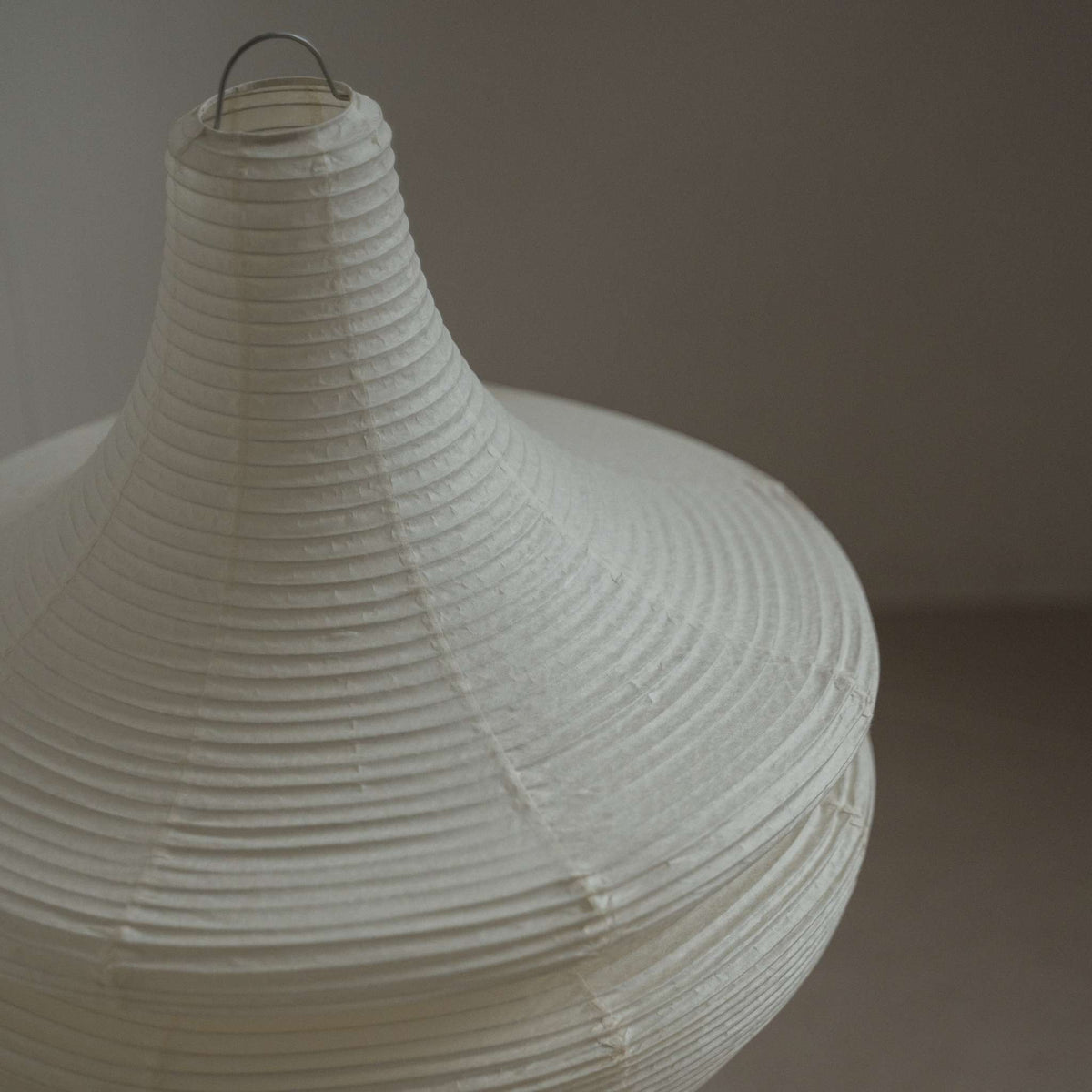 Gedetailleerde close-up van de taps toelopende bovenkant en geribbelde textuur van het Harusame Mino Washi-papier op de Gemini 02 lamp