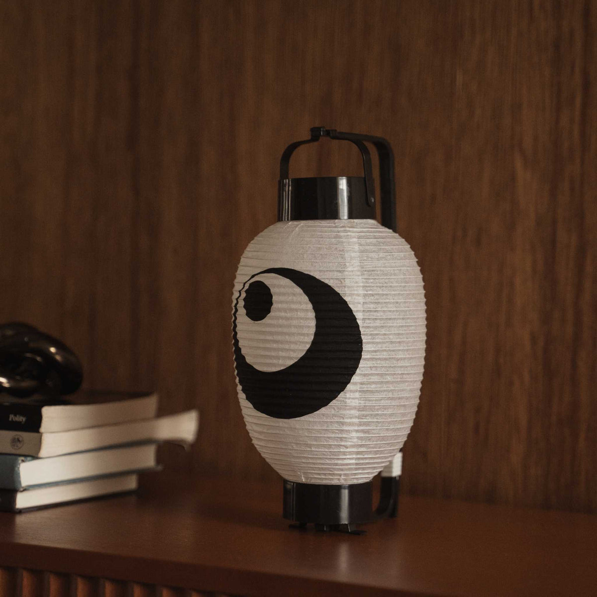 Japanese paper lantern chochin on a dark wooden table displaying the traditional black ink design.