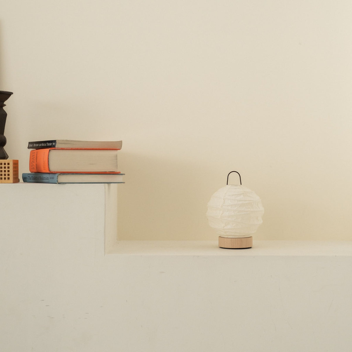 Onverlichte ronde Japanse papieren tafellamp "Yuhi" geplaatst op een witte console tafel in een minimalistische Japandi woonkamer.