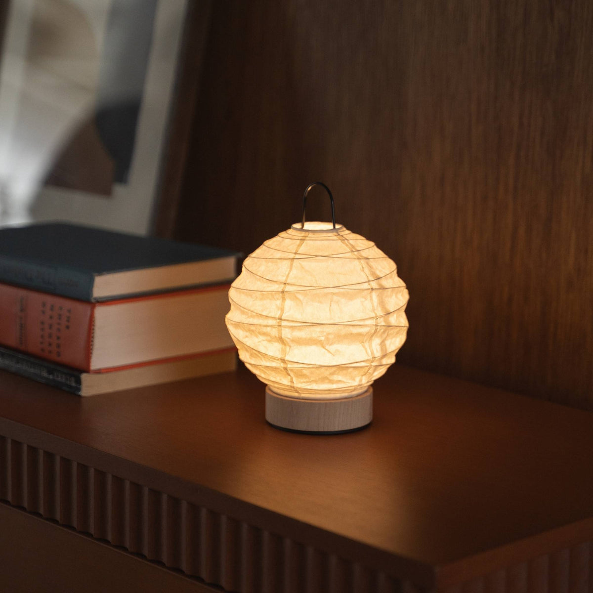 Japanse papieren tafellamp "Yuhi" die een warme gloed uitstraalt op een mid-century modern dressoir.