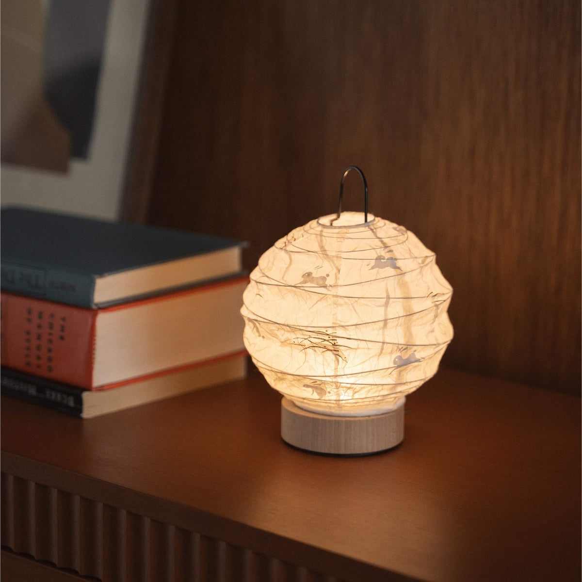 Japanse papieren tafellamp "Yuhi" die een warme gloed uitstraalt op een mid-century modern dressoir.