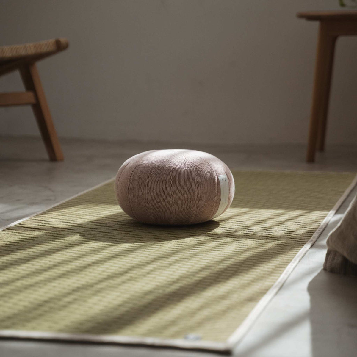 Misty rose japanese zafu meditation cushion sitting on a tatami mat creating a calm atmosphere for mindfulness.