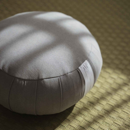 Detailed view of silver gray zafu meditation cushion highlighting the suede like fabric texture on a tatami mat.