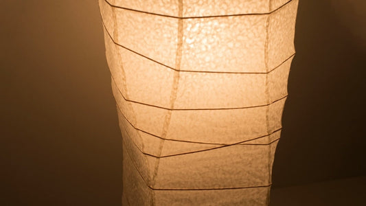 A close-up view of the lower part of a Japanese washi paper lamp, shot from above, showcasing its elegant curves and warm light