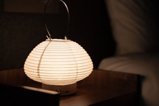 Japanese paper lamp "Rin" emitting warm glow and atmosphere in bedroom