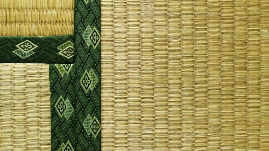 Close up view of traditional tatami mat showing the woven texture and a green decorative fabric border with diamond patterns.