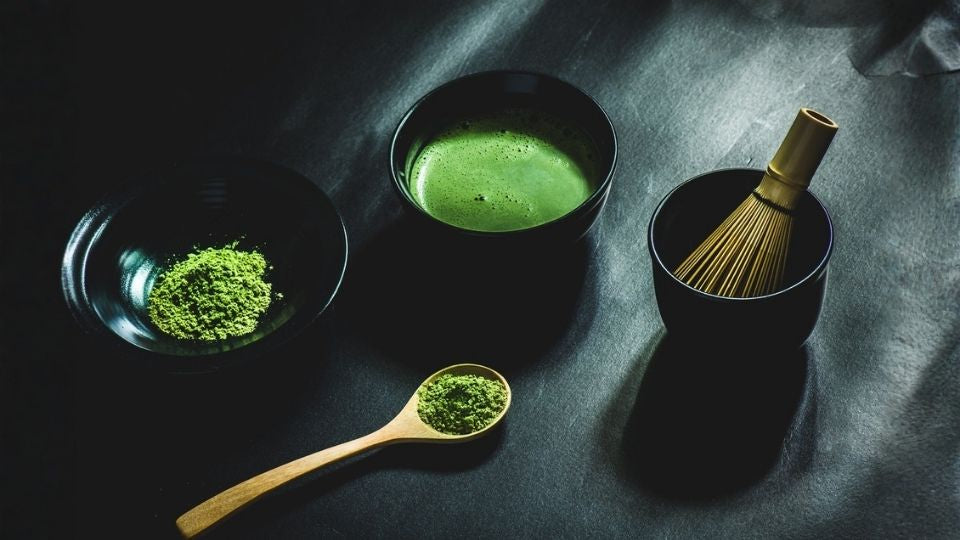 Refreshing iced green tea served in a clear glass matcha bowl with ice cubes, illustrating a summer style of matcha.
