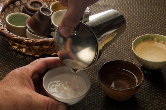 Une scène de saké versé d'une bouteille de saké (tokkuri) dans une tasse à saké.