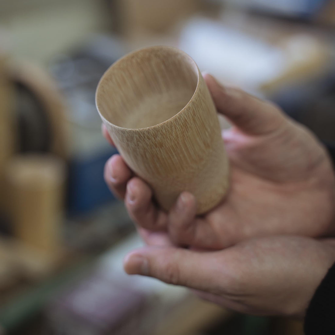 A hand holding a cup made from Japanese bamboo