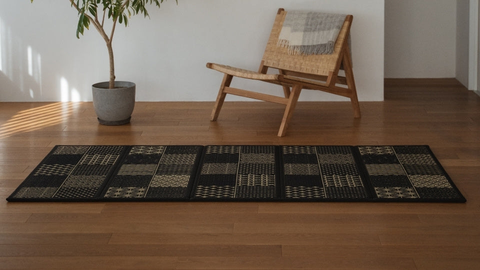 Japanese long black tatami mat with geometric patterns on a japandi living room floor creating a sophisticated zen decor atmosphere.