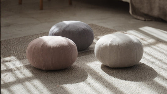 Three round zafu meditation cushions placed on the floor near a bed with linen sheets in a cozy room.