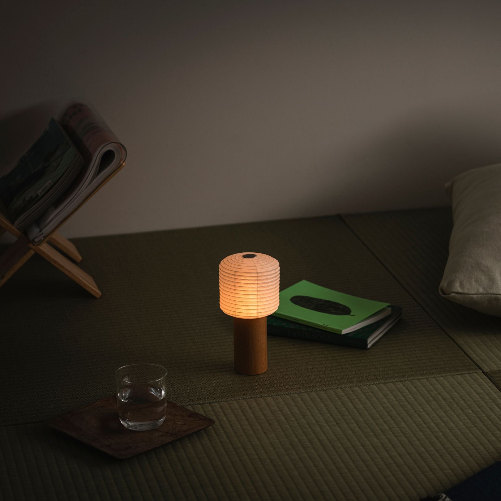 A portable paper table lamp glowing warmly, placed on a traditional Japanese tatami mat