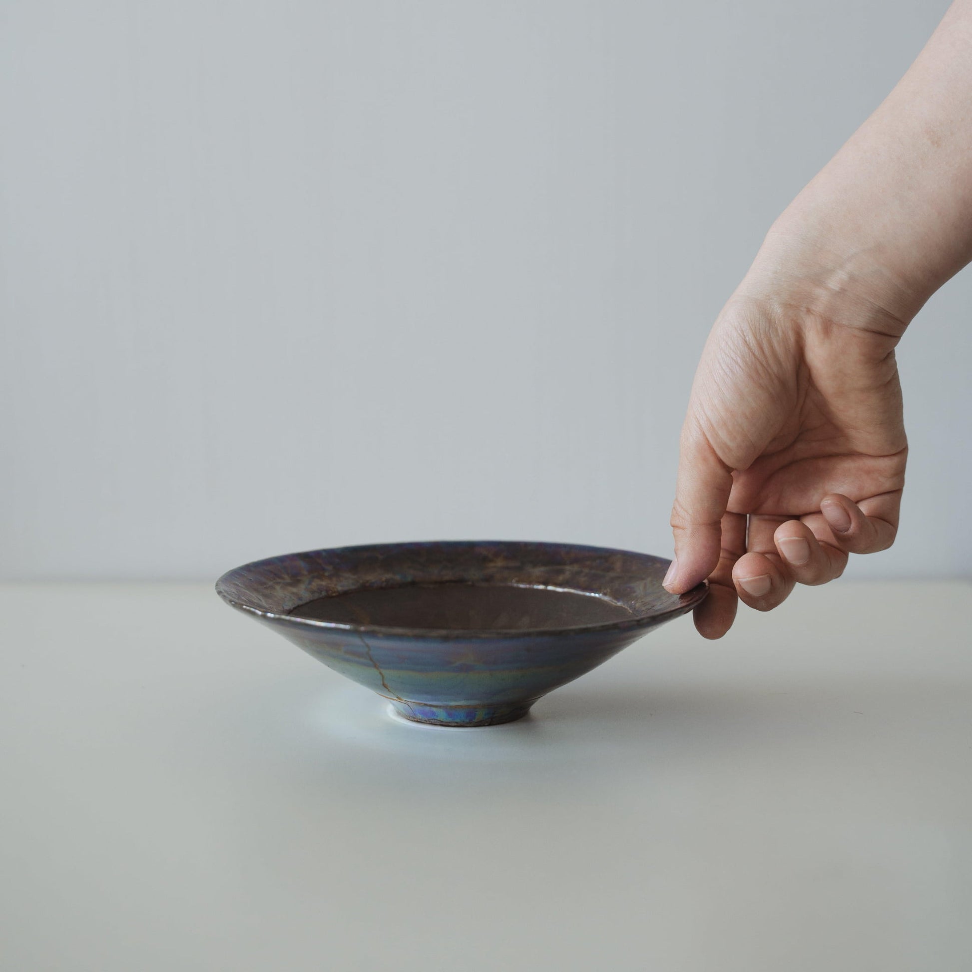 Japanese Kintsugi bowl in deep brown with a gold repair, showcasing the beauty of imperfection.