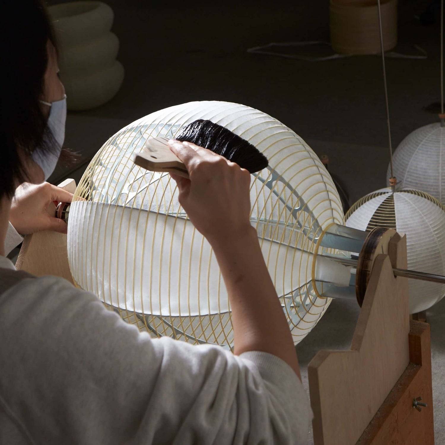 A craftsman attaching washi paper to a lantern frame made from bamboo skewers.