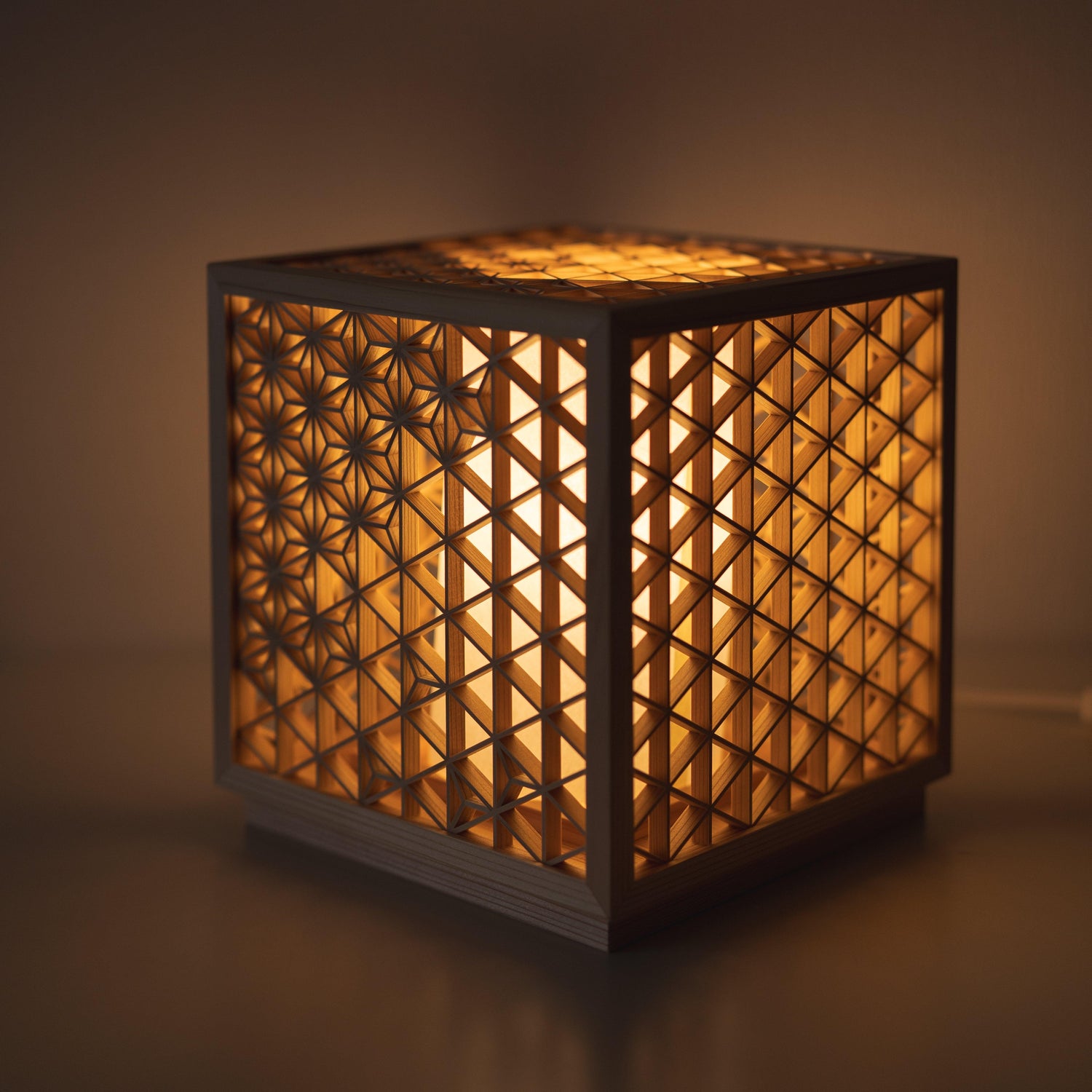 Japanese lamp meticulously handcrafted using the 1400-year-old "kumiko" technique, assembling 600 pieces of premium Akita cedar into a mesmerizing cubic form.