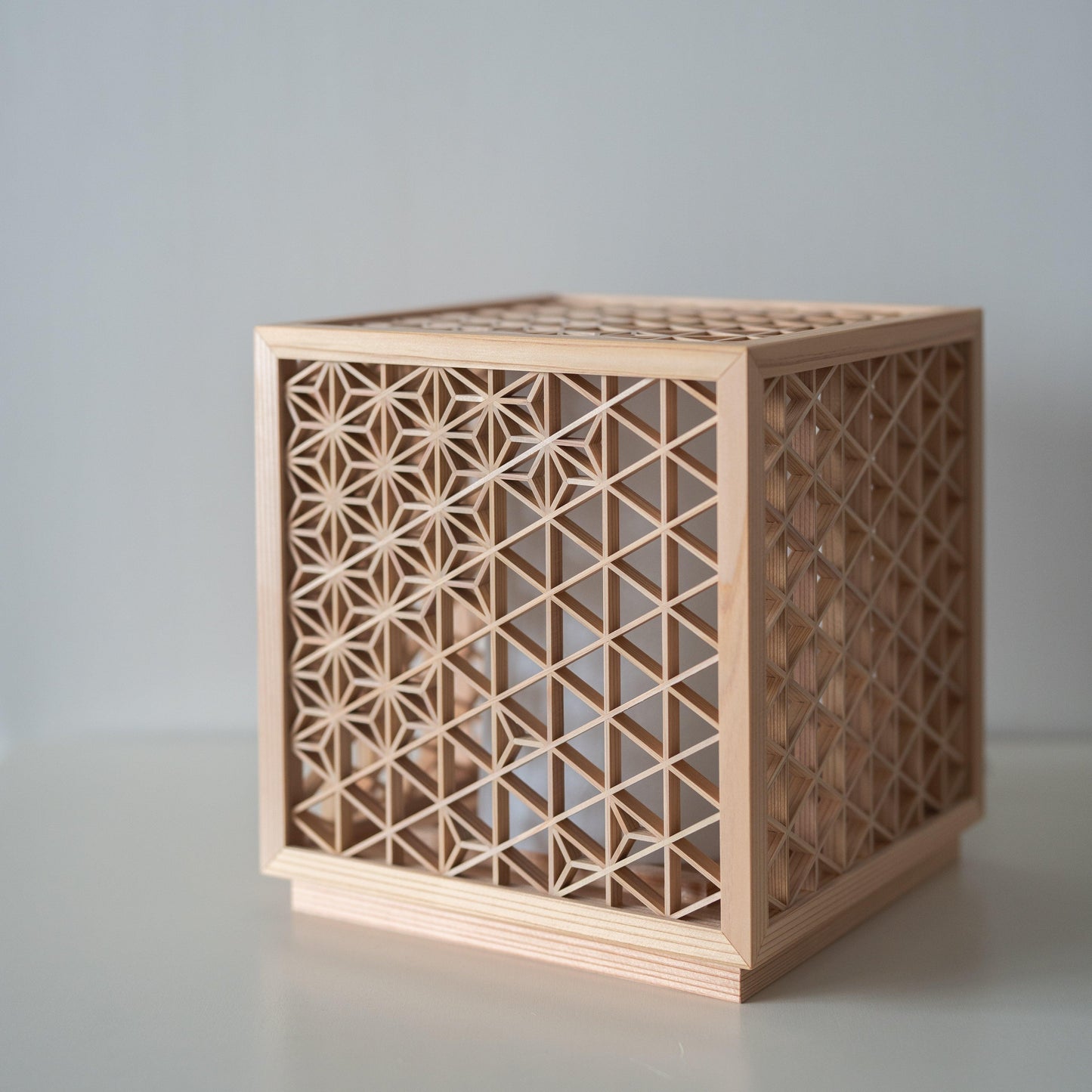 Japanese lamp meticulously handcrafted using the 1400-year-old "kumiko" technique, assembling 600 pieces of premium Akita cedar into a mesmerizing cubic form.