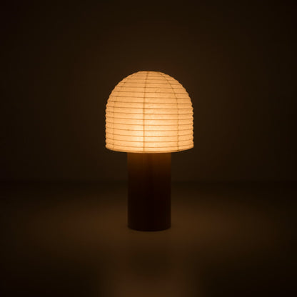 A portable Yame lantern with a wooden handle and bell-shaped top, glowing warmly in a dark room