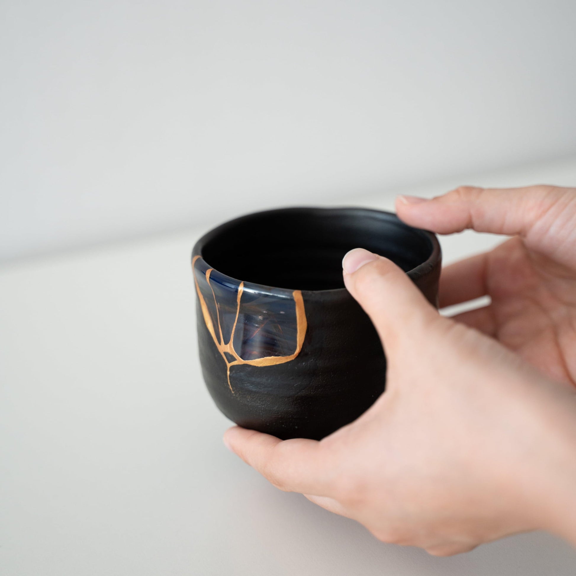 Black Kintsugi tea bowl repaired with blown glass using the Yobitsugi technique, the most challenging of Kintsugi techniques, presented in a paulownia wood box.