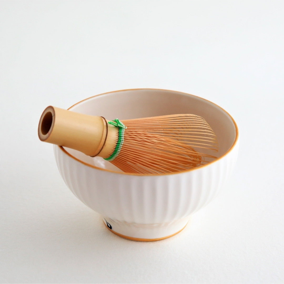 A delicate Japanese matcha bowl “Waraku” accompanied by a bamboo whisk, representing the artistry of Buzan Kiln and the 1,500-year tradition of Mino Ware pottery.