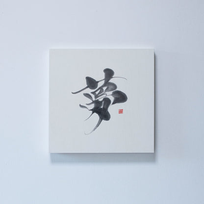 Square panel displaying Japanese calligraphy of the character '夢' (dream) on white rice paper, mounted on a white wall