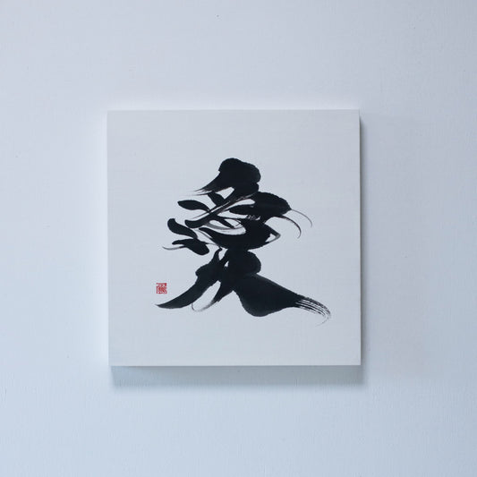 Square panel featuring Japanese calligraphy of the character '愛' (love) on white rice paper, mounted on a white wall