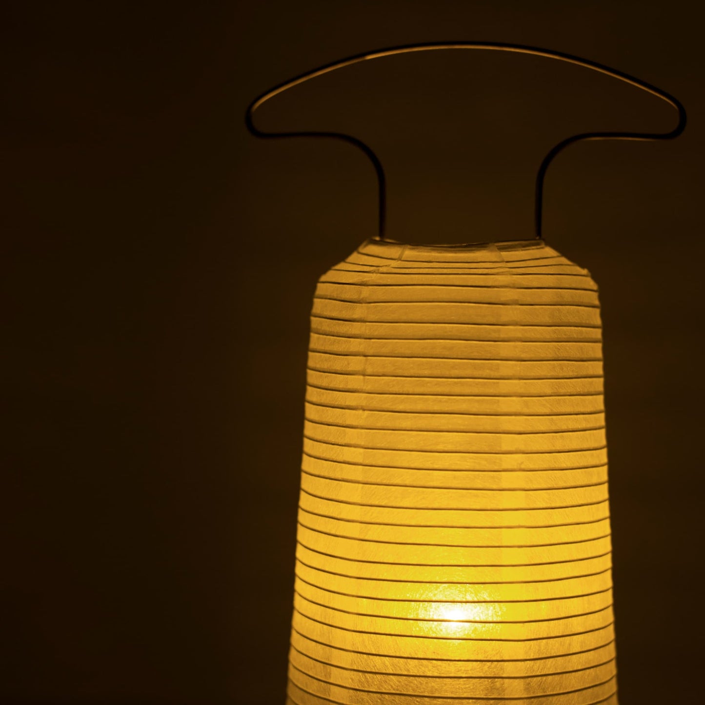 Close-up of a traditional Japanese paper lantern emitting warm light in a dark room