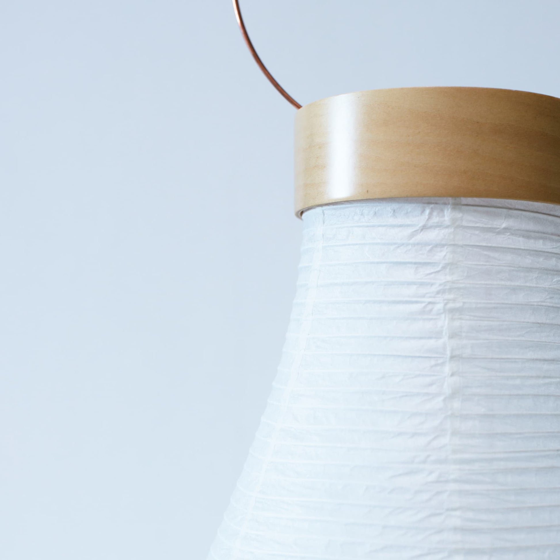 A close-up of a traditional Japanese paper lantern with bright white wallpaper