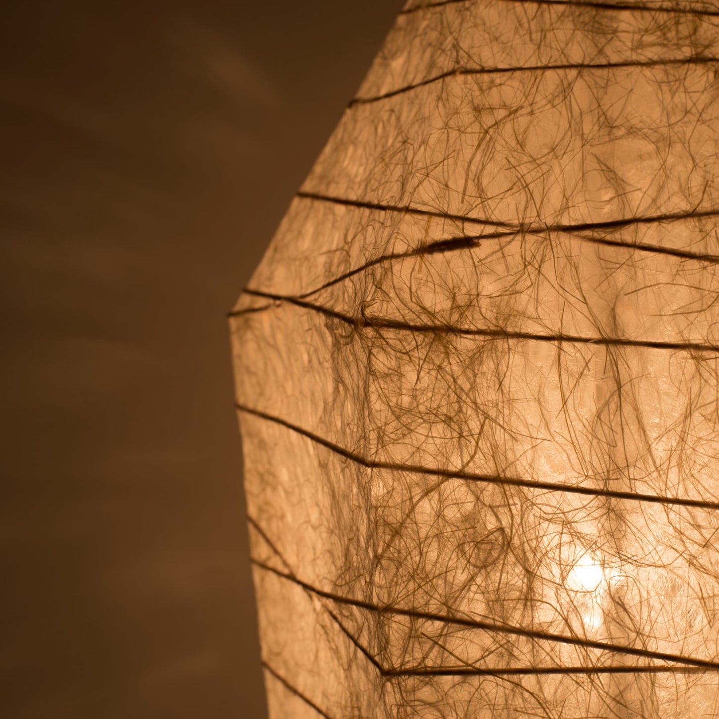 Close-up of Japanese floor lamp made from washi paper with intricate patterns diffusing warm light, ice stone design