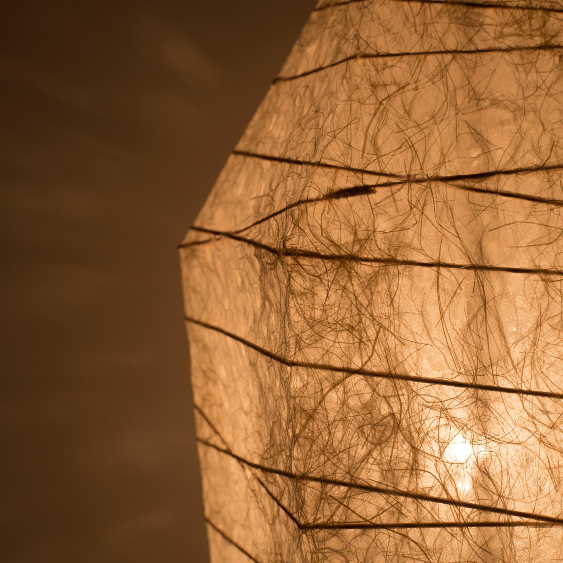 Close-up of Japanese floor lamp made from washi paper with intricate patterns diffusing warm light, ice stone design