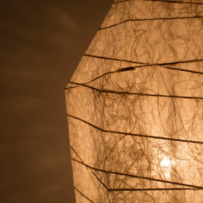 Close-up of Japanese floor lamp made from washi paper with intricate patterns diffusing warm light, ice stone design