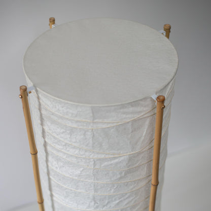 Close-up of the top section of a cylindrical Japanese lamp with bamboo frame and washi paper, white background