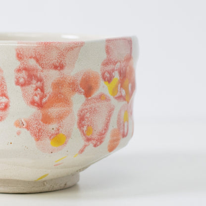 Close-up of matcha chawan bowl "Flower" with red-orange glaze evoking spring petals.