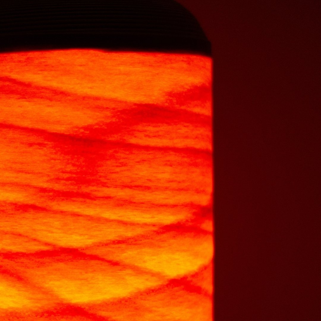 Close-up of Japanese living room lamp glowing like a bonfire through thin beech wood slats.