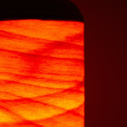 Close-up of Japanese living room lamp glowing like a bonfire through thin beech wood slats.