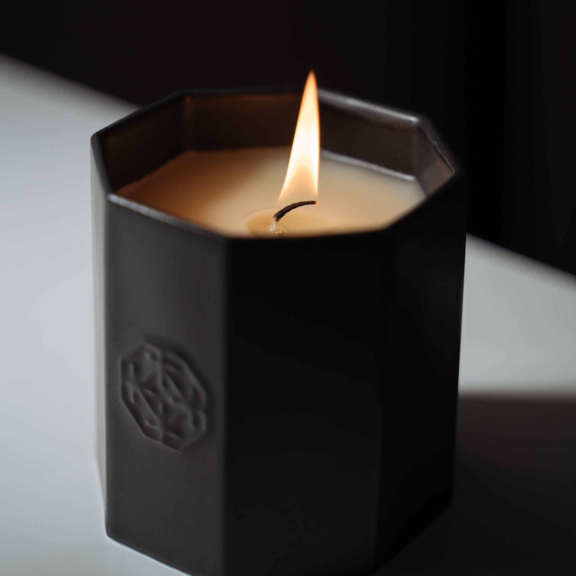 A lit black scented candle made of Arita ware, offering a relaxing wooden fragrance.