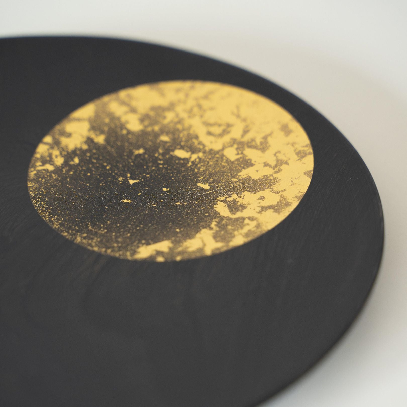 A close-up of a Japanese lacquerware plate featuring a moon design in gold leaf.