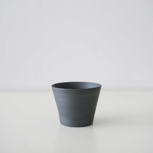 A simple black conical teacup made of traditional Banko ware.