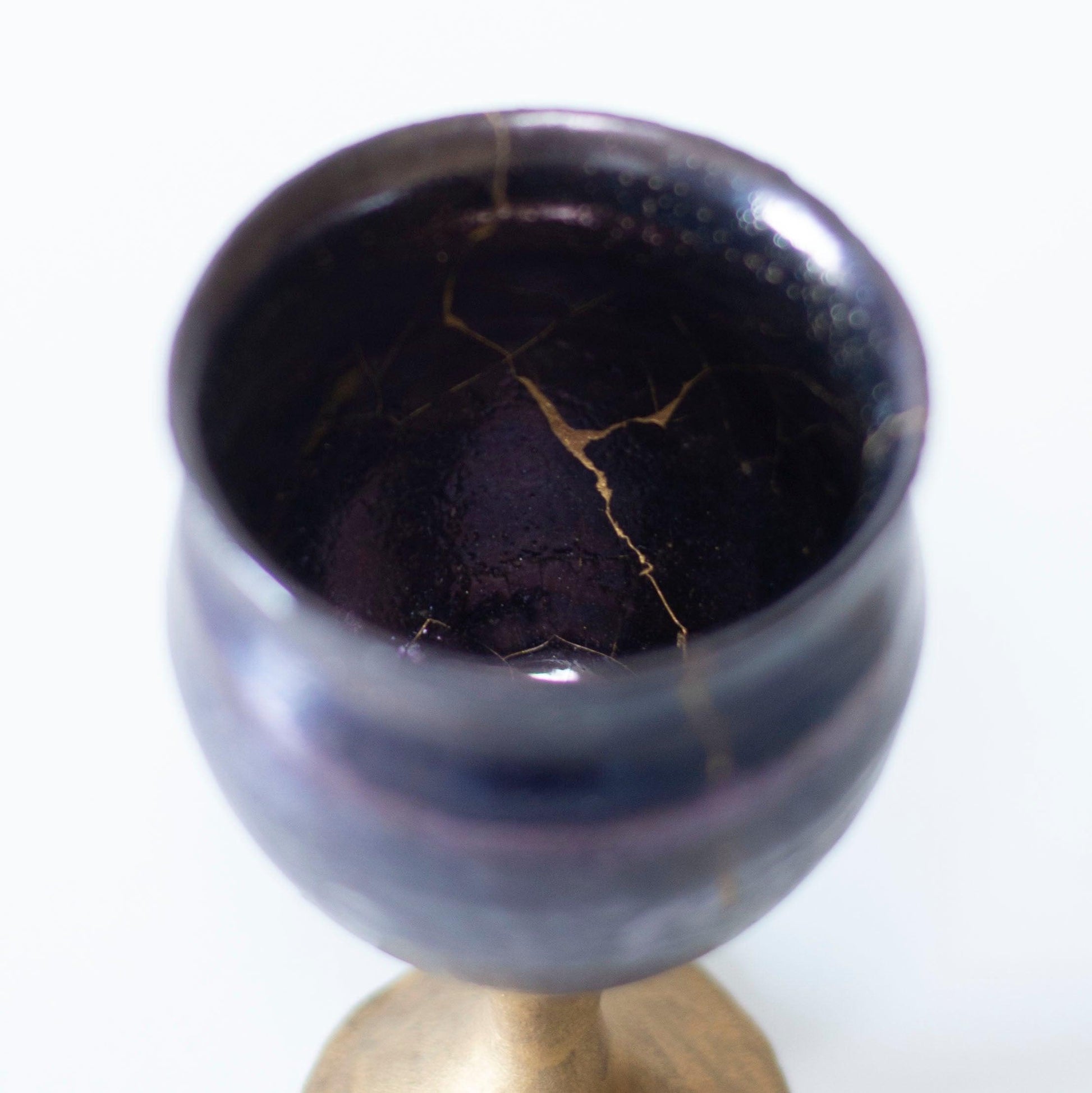 The interior of a magenta wine goblet, revealing the delicate kintsugi repair and the unique color combination.