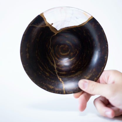 A hand holding a Kintsugi bowl, showcasing the weight and balance of the piece.