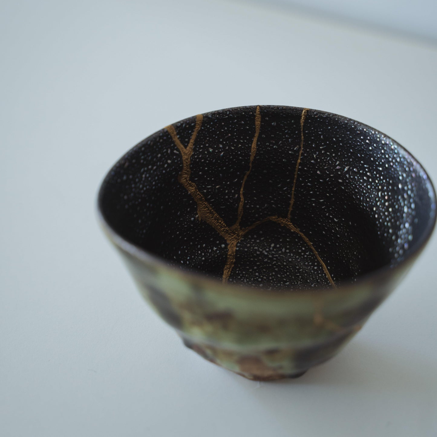 Inside of a deep green tea bowl repaired with Kintsugi, a traditional Japanese technique, showcasing the beauty of imperfection.