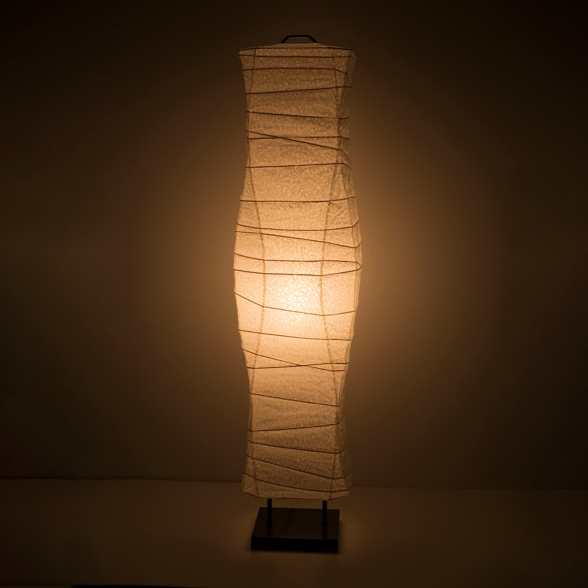 A front view of a Japanese washi paper lamp with smooth, flowing curves and a warm light on a dark brown background