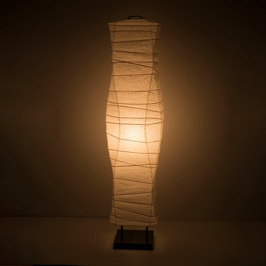 A front view of a Japanese washi paper lamp with smooth, flowing curves and a warm light on a dark brown background