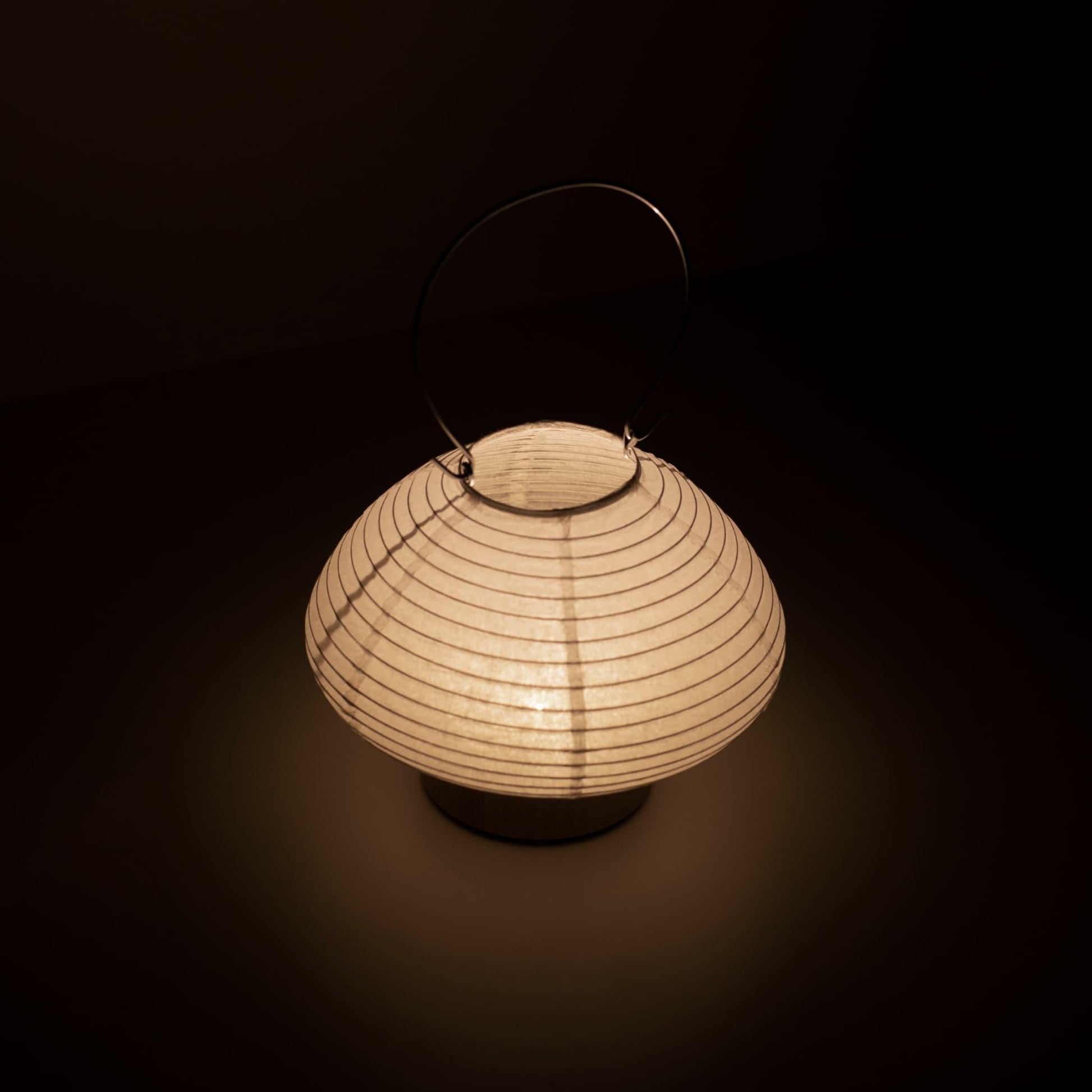 Detail of a portable paper table lamp crafted with Gifu lantern techniques and Mino washi paper, emitting a soft, warm light.