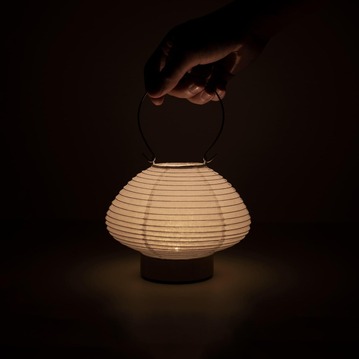 Detail of a portable table lamp crafted with Gifu lantern techniques and Mino washi paper, emitting a soft, warm light.