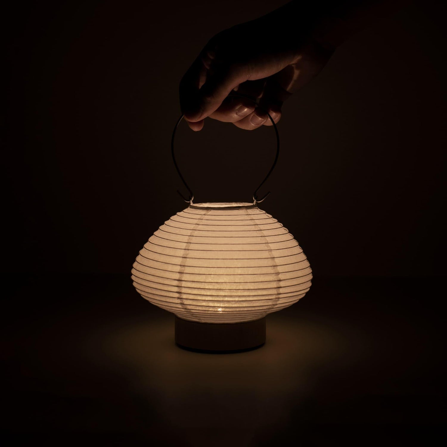 Detail of a portable table lamp crafted with Gifu lantern techniques and Mino washi paper, emitting a soft, warm light.