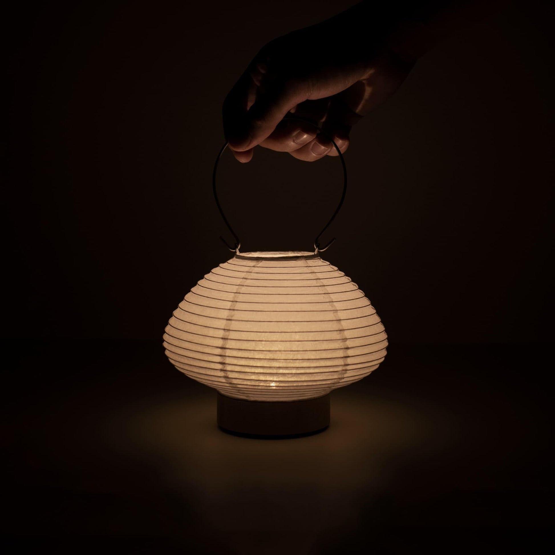 Detail of a portable table lamp crafted with Gifu lantern techniques and Mino washi paper, emitting a soft, warm light.