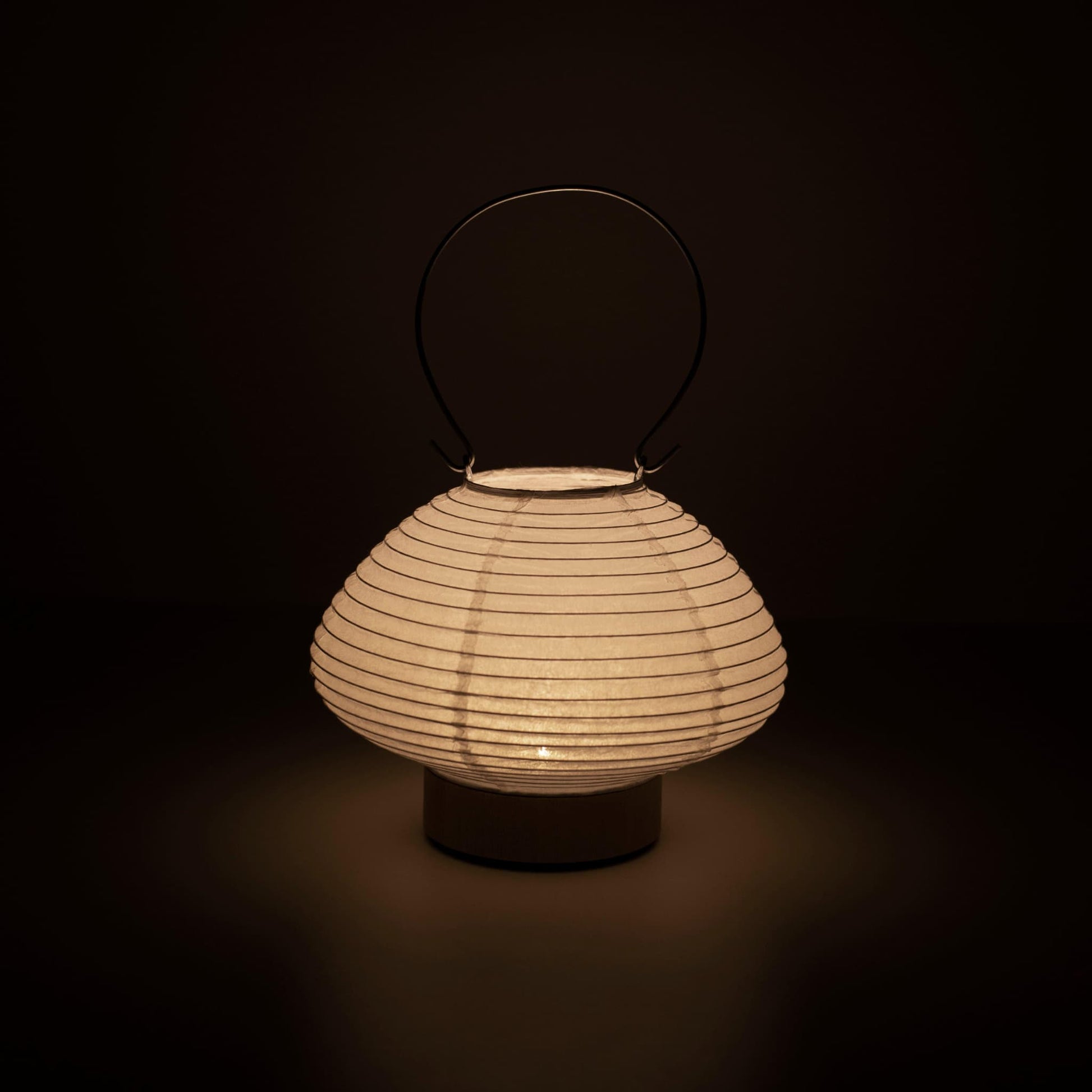 Hand holding a portable table lamp resembling a traditional Japanese lantern, crafted with Gifu lantern techniques and Mino washi paper.