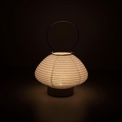 Hand holding a portable table lamp resembling a traditional Japanese lantern, crafted with Gifu lantern techniques and Mino washi paper.