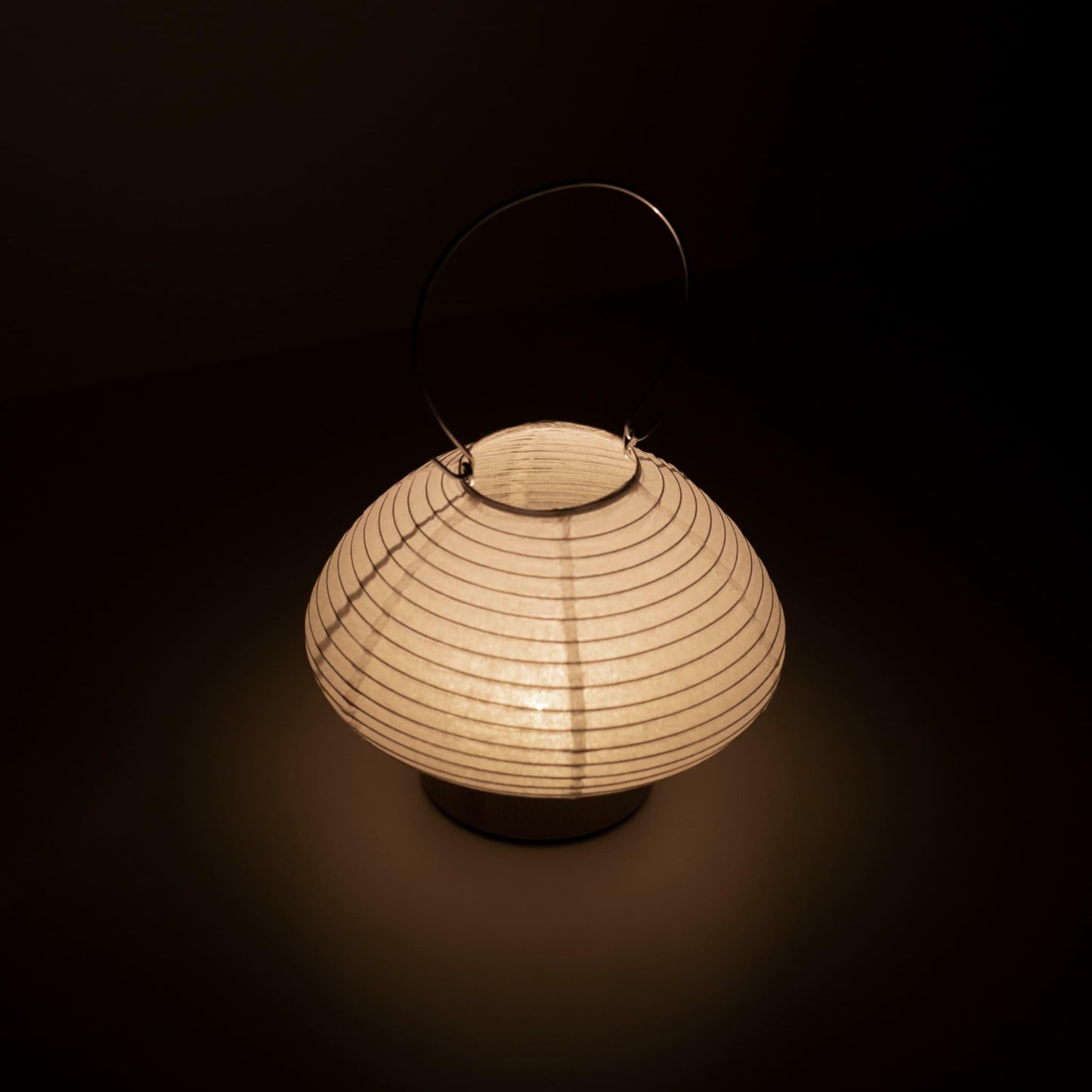 Detail of a portable table lamp crafted with Gifu lantern techniques and Mino washi paper, emitting a soft, warm light.